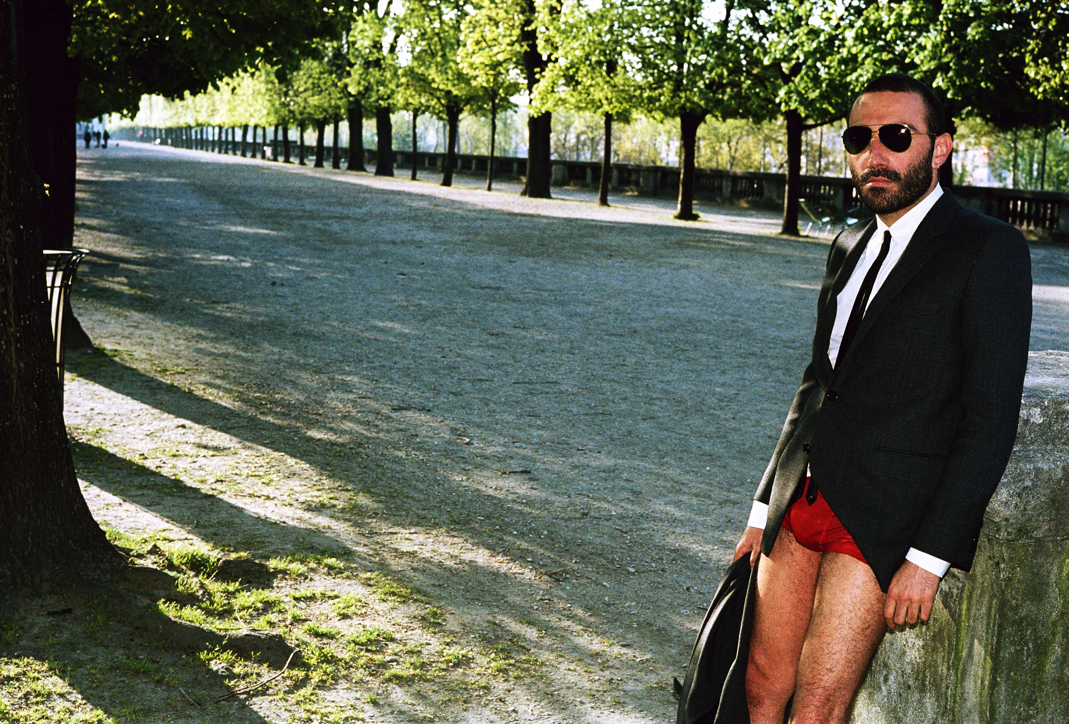 MASSES Magazine No. 12 – Aux Armes et Cætera, Photography by Matthias Vriens – Pierre-Ange Carlotti wearing Celine by Hedi Slimane Autumn/Winter 2019 jacket, shirt, trousers, tie and sunglasses, with red underwear — 2019